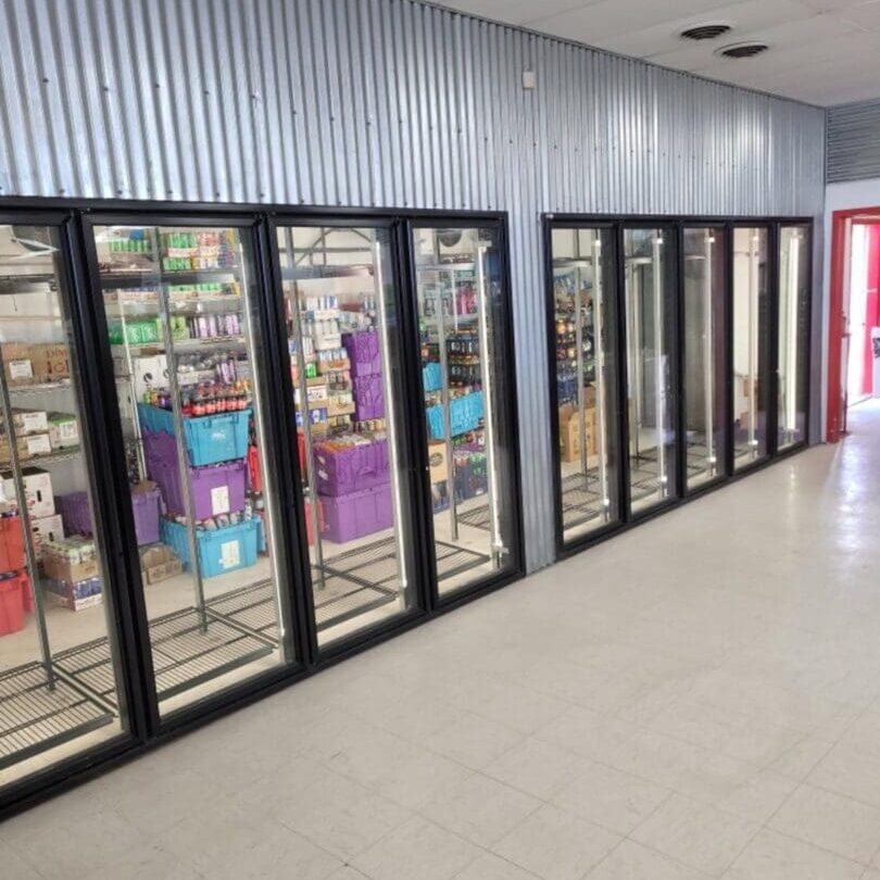 A row of refrigerators in an empty room.