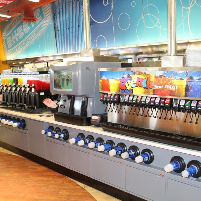 A row of soda machines in front of a wall.