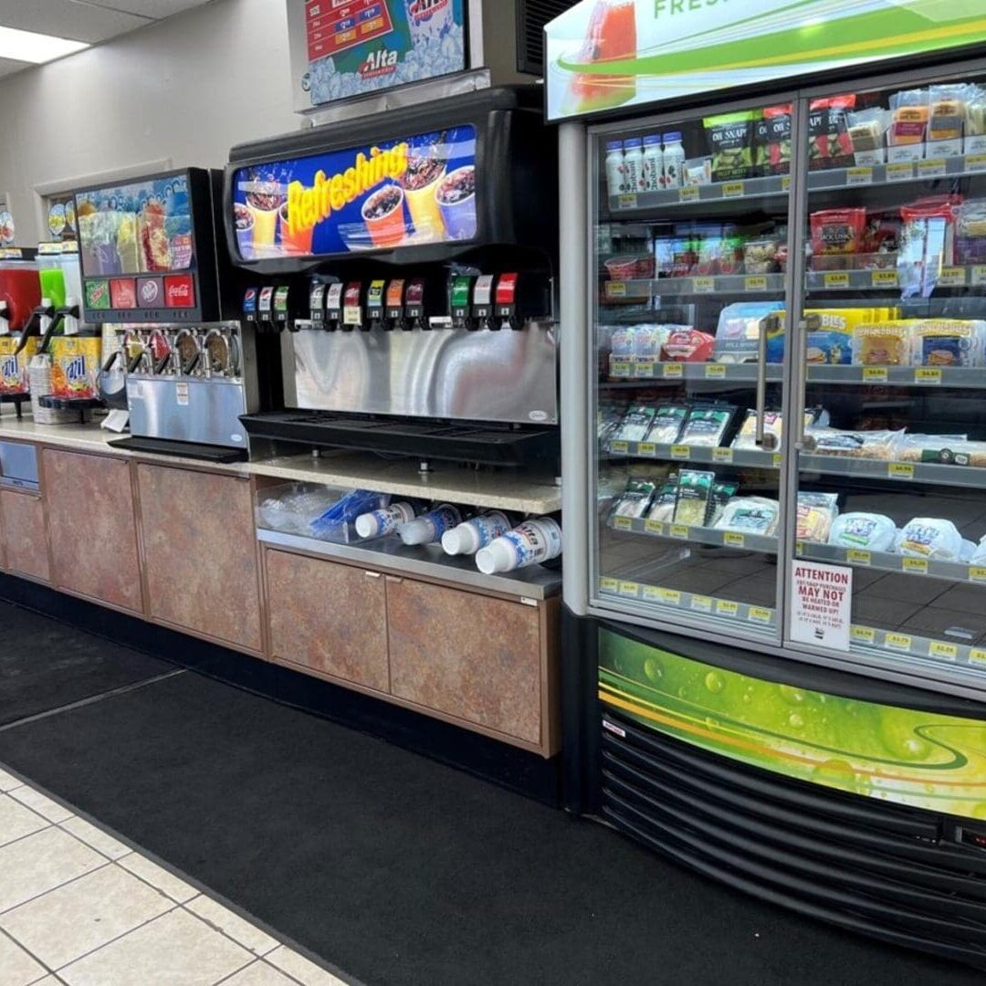 A convenience store with refrigerators and drinks on the shelves.